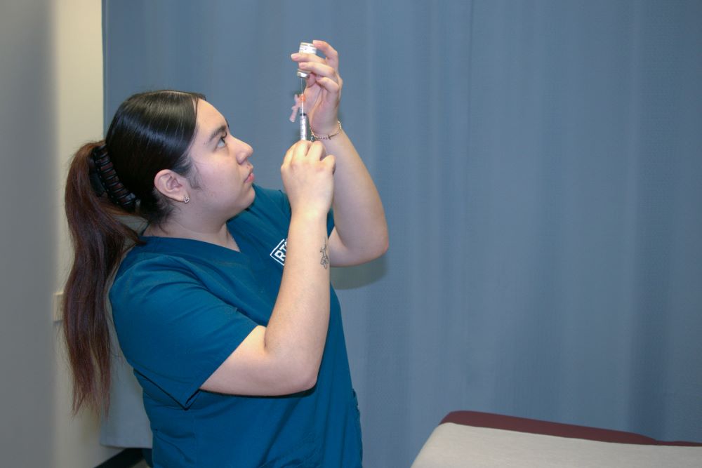 Valeria Hurtado-Gonzalez using a syringe to extract liquid from a medical vial.