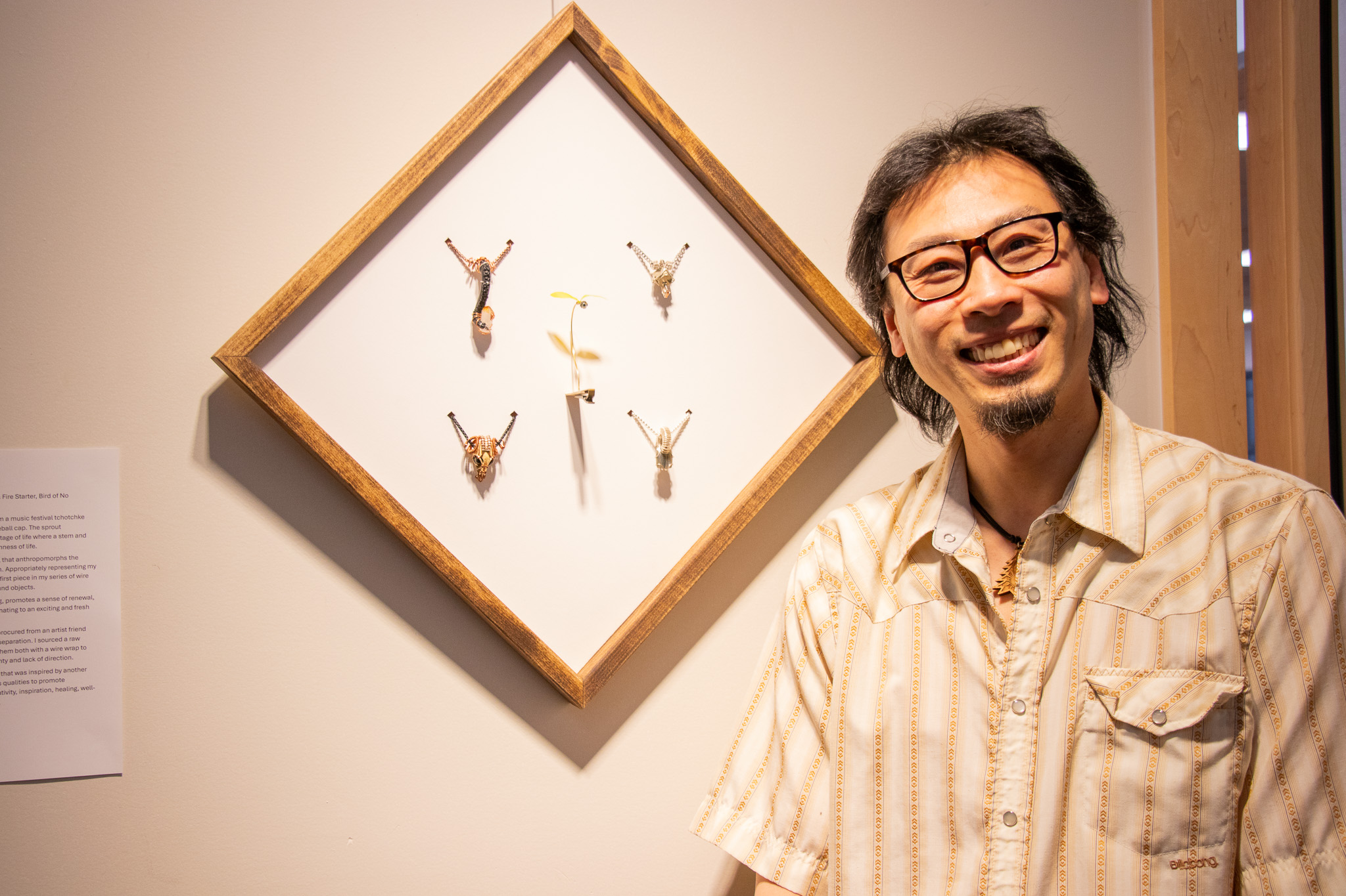 Mike Choi smiling next to his hand-made pendants