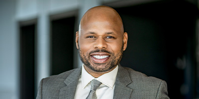 Dante King in a grey suit, smiling