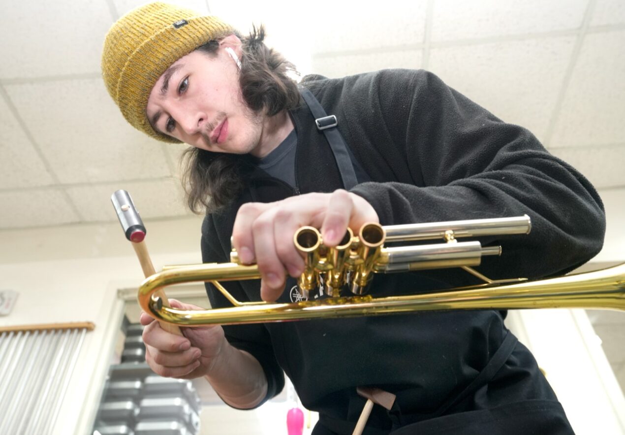 A student repairing a trumpet.