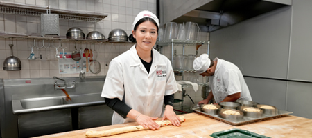 A culinary arts student rolling out dough.